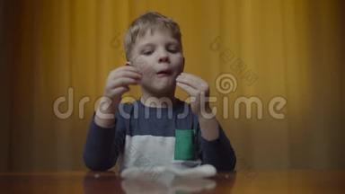 金发男孩在家里的桌子上吃着薯片，做着滑稽的食物眼睛。 男孩喜欢吃零食和玩耍